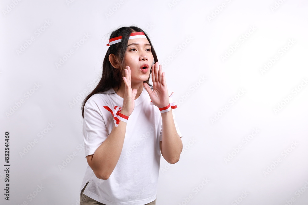 Young beautiful woman wearing a red white flag ribbon shouting and screaming loud with a hand on her mouth. Indonesia's independence day concept. Young beautiful woman wearing a red white flag ribbon shouting and screaming loud with a hand on her mouth. Indonesia's independence day concept.