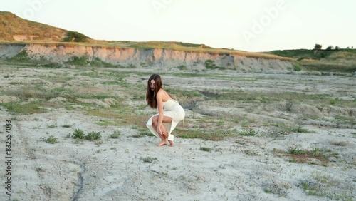Wallpaper Mural The elegant girl in a dress strokes the earth, rises, and dances on the cracked ground in the summer at sunset. A choreographer's dance in nature. Feminine energy. Torontodigital.ca
