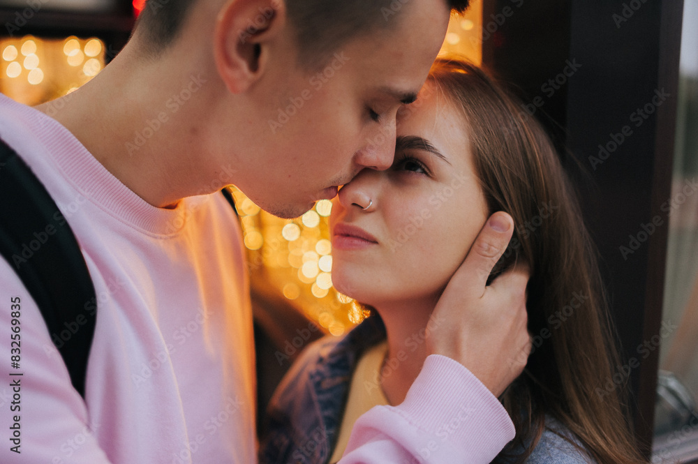 Naklejka premium A happy young couple in love, a boy and a girl, on a walk in the city, hugging and walking. Urban European love story and photo shoot