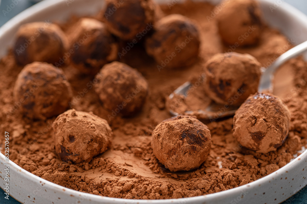 Fototapeta premium Artisanal chocolate truffles dusted with cocoa powder on a plate with a spoon