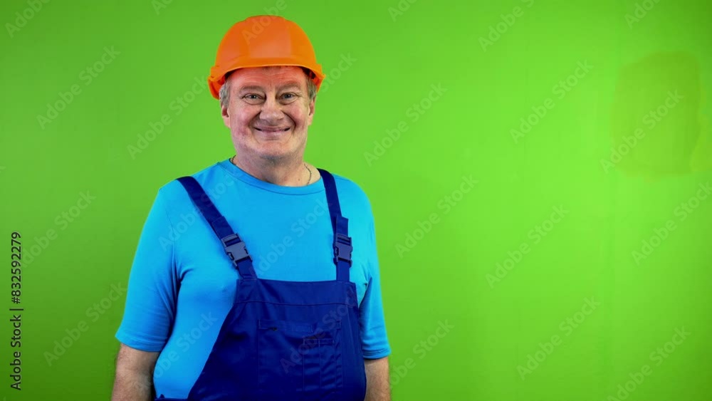 Senior worker in overalls and helmet looking at camera and smiling. Senior worker in overalls and helmet looking at camera and smiling.