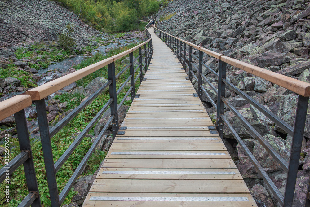 wooden footpath with guardrail crossing a rocky valley in a sweden national park