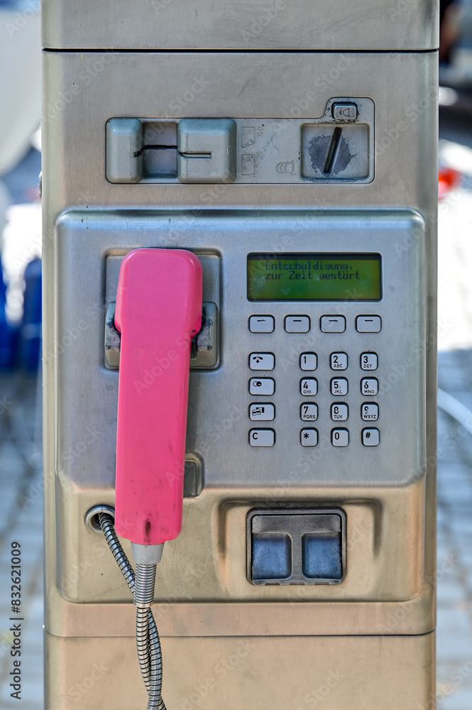 Telefonzelle, alte rote Telefonzelle, altes Münztelefon auf einer Edelstahlsäule, mit rosa Telefonhörer, Tastatur und Münzeinwurf, Deutschland Telefonzelle, alte rote Telefonzelle, altes Münztelefon auf einer Edelstahlsäule, mit rosa Telefonhörer, Tastatur und Münzeinwurf, Deutschland