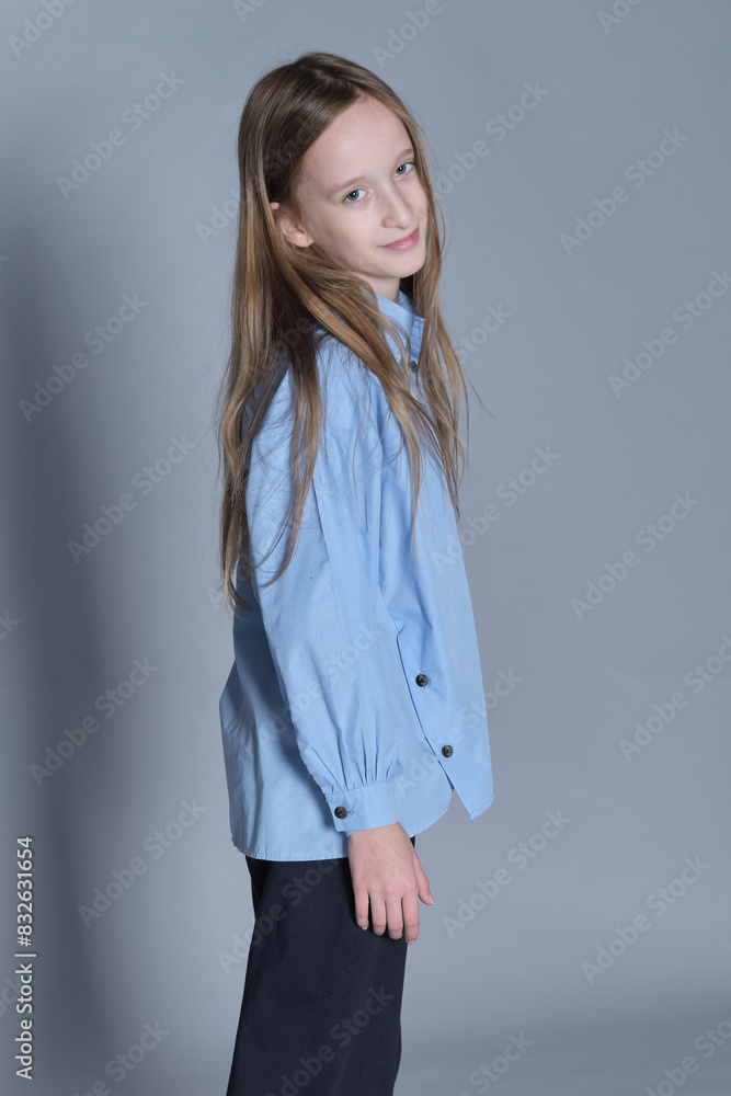 Smiling girl with hands on hips in a blue shirt, exudes confidence. Perfect for themes of youth empowerment and fashion. Smiling girl with hands on hips in a blue shirt, exudes confidence. Perfect for themes of youth empowerment and fashion.
