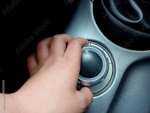 The process of switching the driving modes of a car from front-wheel drive to 4x4 with the help of a round switch. A person switches the driving modes of a car with his hand.