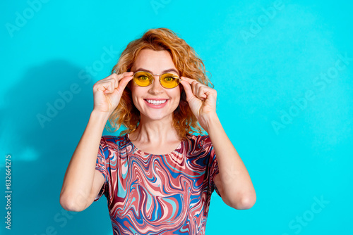 Photo of pretty woman beaming smile touch sunglass wear t-shirt isolated on teal color background