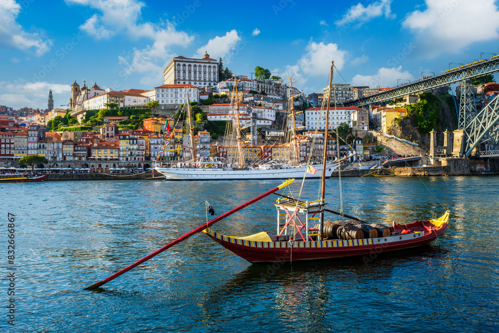 Obraz premium View of Porto city and Douro river with traditional boats with port wine barrels and sailing ship from famous tourist viewpoint Marginal de Gaia riverfront. Porto, Vila Nova de Gaia, Portugal