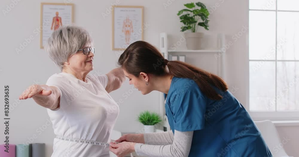 Senior woman, nurse in measure waist using a tape measure, taking body measurements. Old woman during examination, regular clinic check up, doctor monitoring elderly person body, weight, slimming Senior woman, nurse in measure waist using a tape measure, taking body measurements. Old woman during examination, regular clinic check up, doctor monitoring elderly person body, weight, slimming