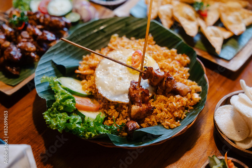 Photography Nasi goreng with fried egg and skewers served on a banana leaf