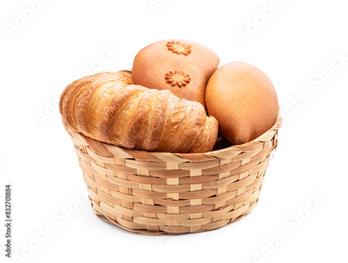 Assortment of baked buns in wicker basket isolated on white background