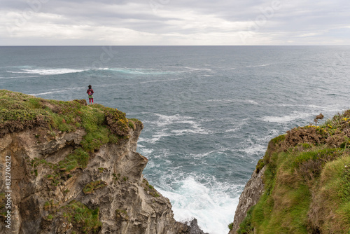 Hiker on a cliff on the Naviega Coast Path. Council of Navia, Asturias