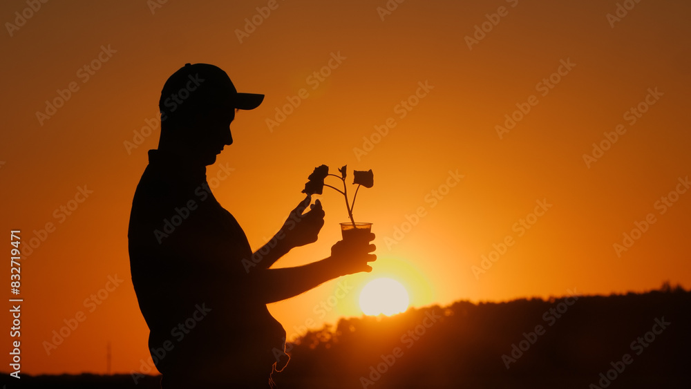 The silhouette of an agronomist holding a pot with a plant ready for planting is visible.