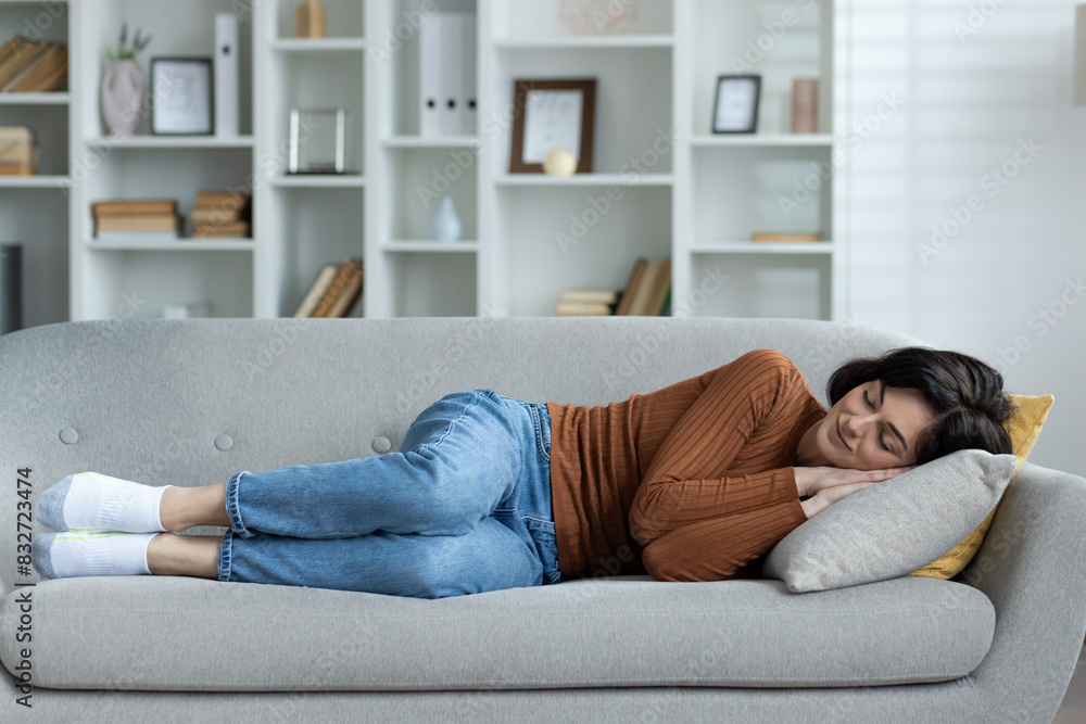 Young woman resting at home, lying on sofa and sleeping relaxed, holding two hands together under head Young woman resting at home, lying on sofa and sleeping relaxed, holding two hands together under head