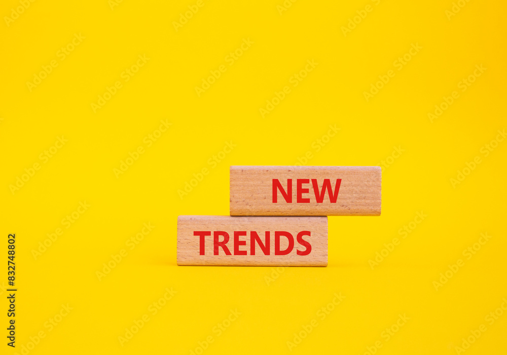 Naklejka premium New Trends symbol. Wooden blocks with words New Trends. Beautiful yellow background. Business and New Trends concept. Copy space.