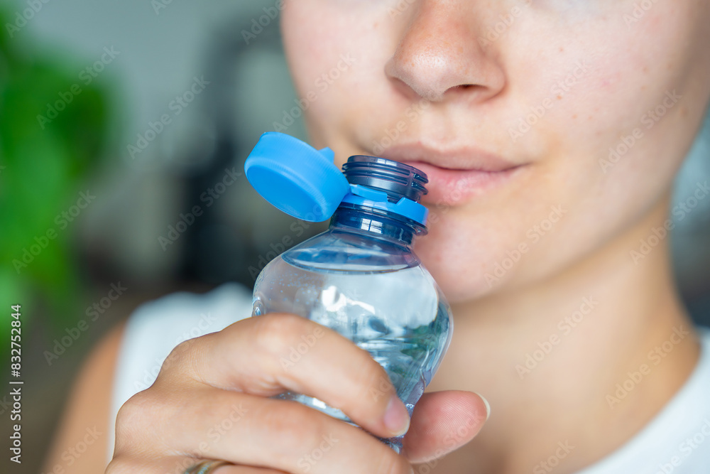 Young woman drinking from a bottle with stationary plastic cap. The new design means the cap remains attached to the bottle after opening, making the entire package easier to collect and recycle Young woman drinking from a bottle with stationary plastic cap. The new design means the cap remains attached to the bottle after opening, making the entire package easier to collect and recycle