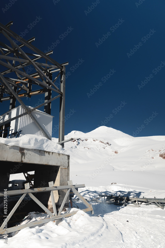 A cable car station high in the mountains under construction. Snowy mountain landscape and construction of a metal structure for a cable car A cable car station high in the mountains under construction. Snowy mountain landscape and construction of a metal structure for a cable car