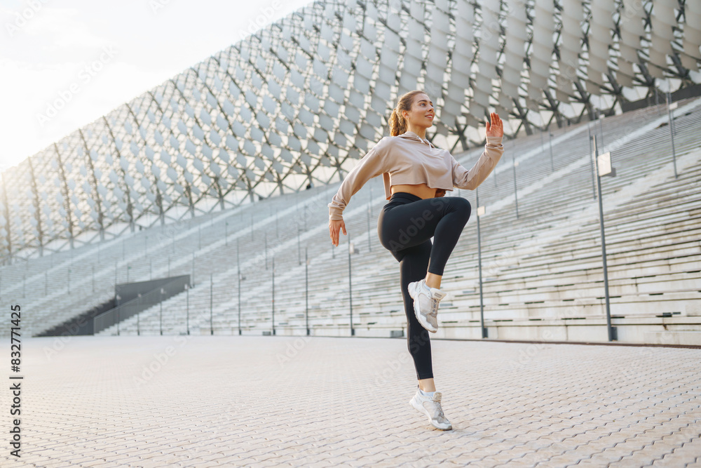 Young woman wearing sports clothes warming up before jogging on the street. People, sport, fitness and flexibility concept