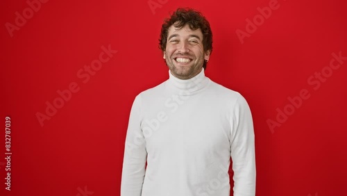 Cheeky young hispanic man wearing a sweater, making a hilarious fish face. his eyes squint in comedy over an isolated bright red backdrop photo