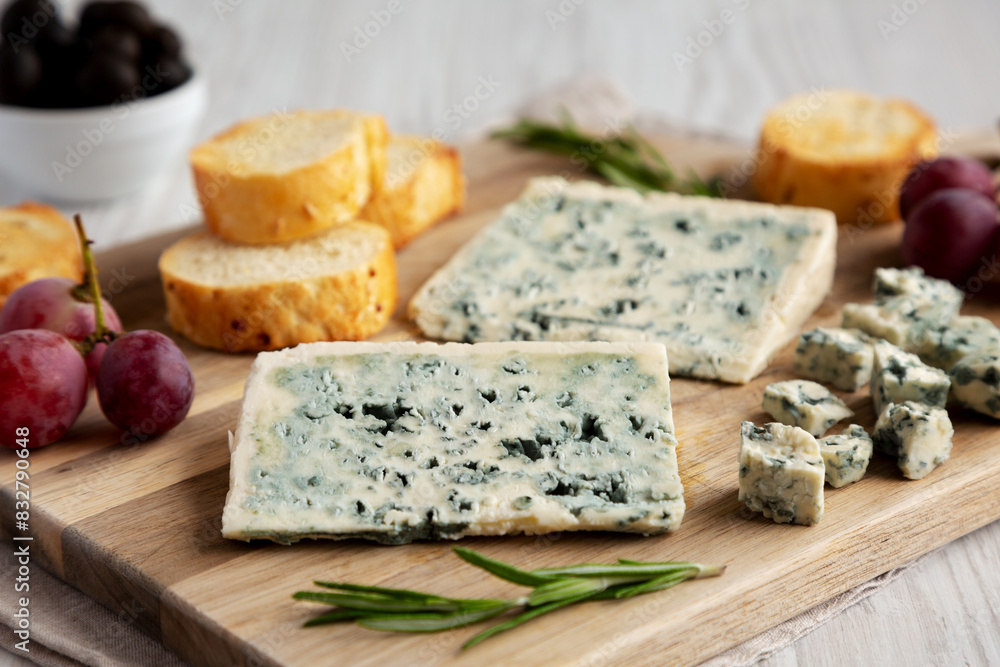 Organic Blue Cheese with Grapes and Olives on a Wooden Board, side view.