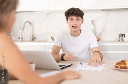 Guy manager tells woman client about specifics of design of microloan, about benefits and advantages. Seller draws up contract on laptop