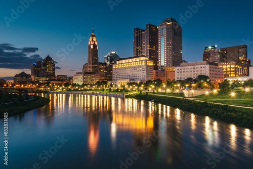 Twilight cityscape with illuminated buildings and river reflections