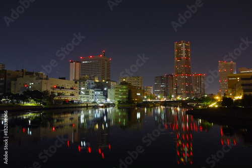 City skyline and buildings reflected in water at night with glowing lights