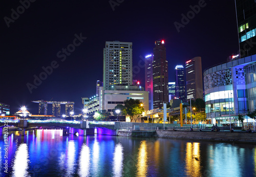 Illuminated city skyline at night by waterfront © Bryan