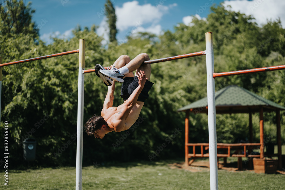 Man doing calisthenics on a horizontal bar in an urban park with lush greenery and a gazebo on a sunny day. Man doing calisthenics on a horizontal bar in an urban park with lush greenery and a gazebo on a sunny day.