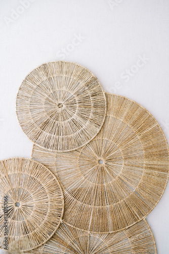 Panel of round woven seaweed rugs hangs on a white wall