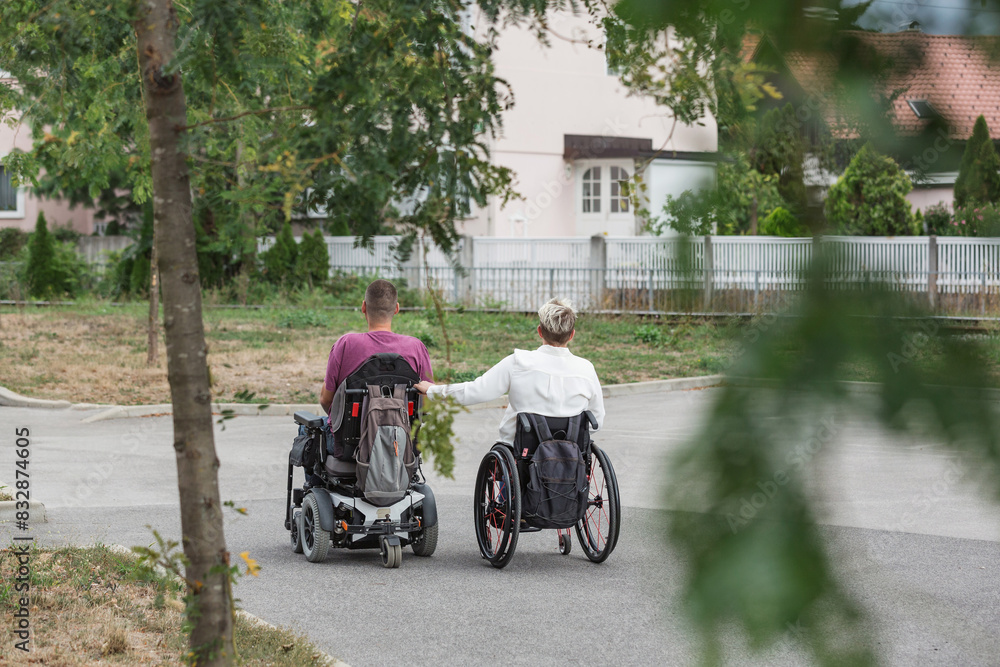 Obraz premium Two friends a woman and a man, wheelchair users spending time outdoors. Life with disability, support, and friendship concepts.