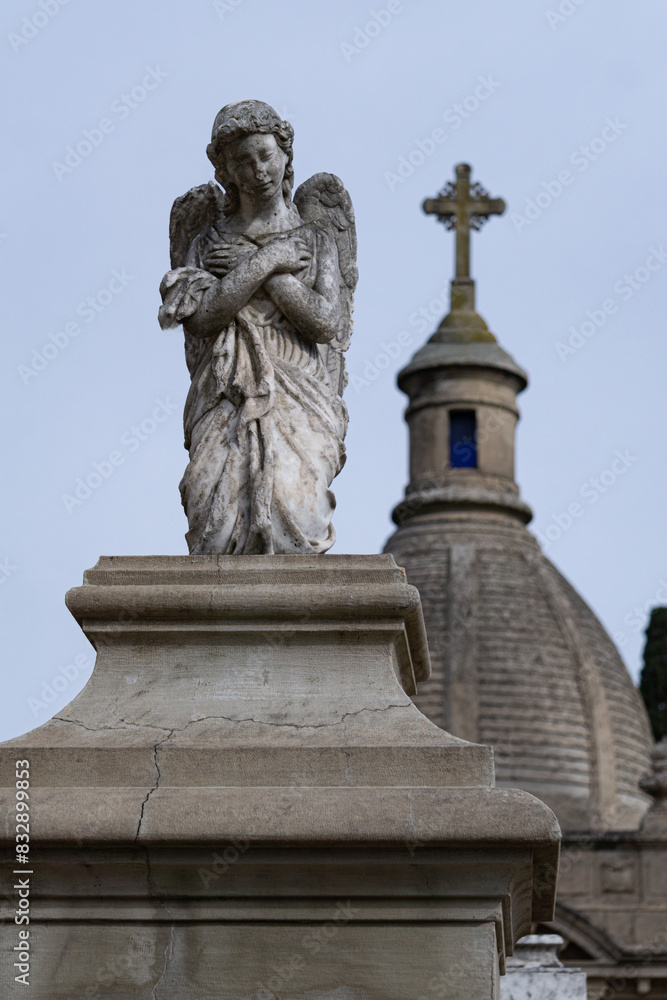 Escultura de un ángel arrodillado con una capilla de fondo Escultura de un ángel arrodillado con una capilla de fondo