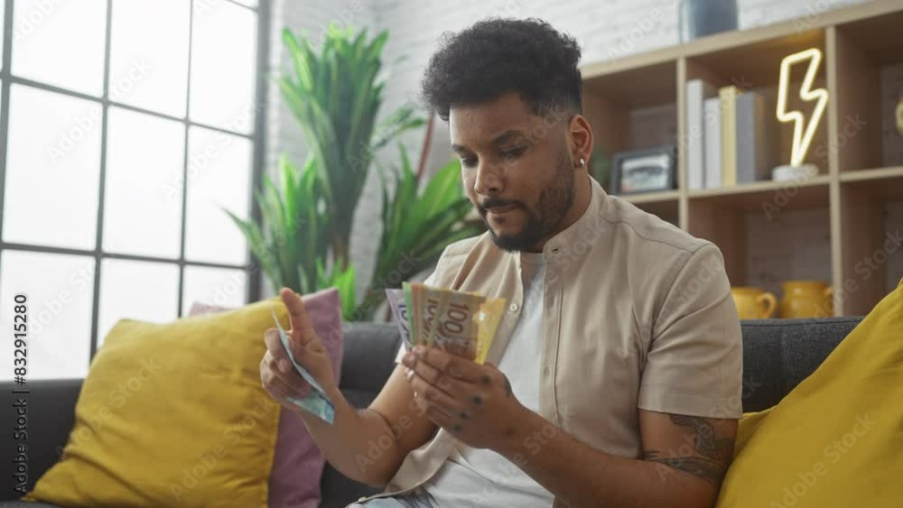 African-american man counting canadian dollars in a modern living room. African-american man counting canadian dollars in a modern living room.