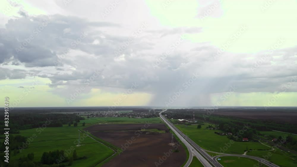 Aerial view of a countryside rainstorm above a highway, contrasting busy roads and serene farmlands Aerial view of a countryside rainstorm above a highway, contrasting busy roads and serene farmlands