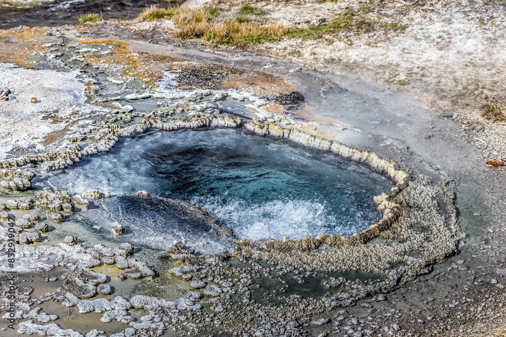 Hot spring in rocky surroundings under sunny skies Hot spring in rocky surroundings under sunny skies