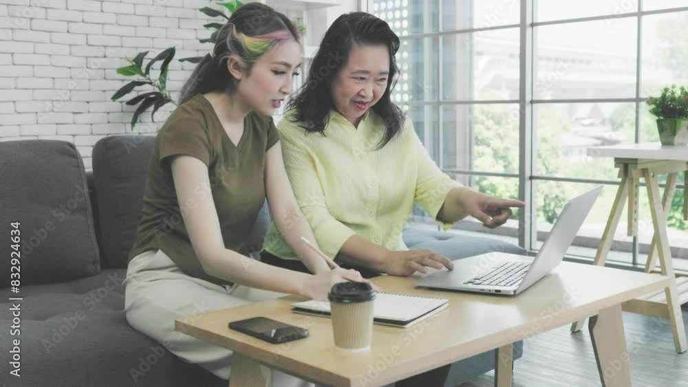 Asian mother and daughter working on computer laptop together at home Asian mother and daughter working on computer laptop together at home
