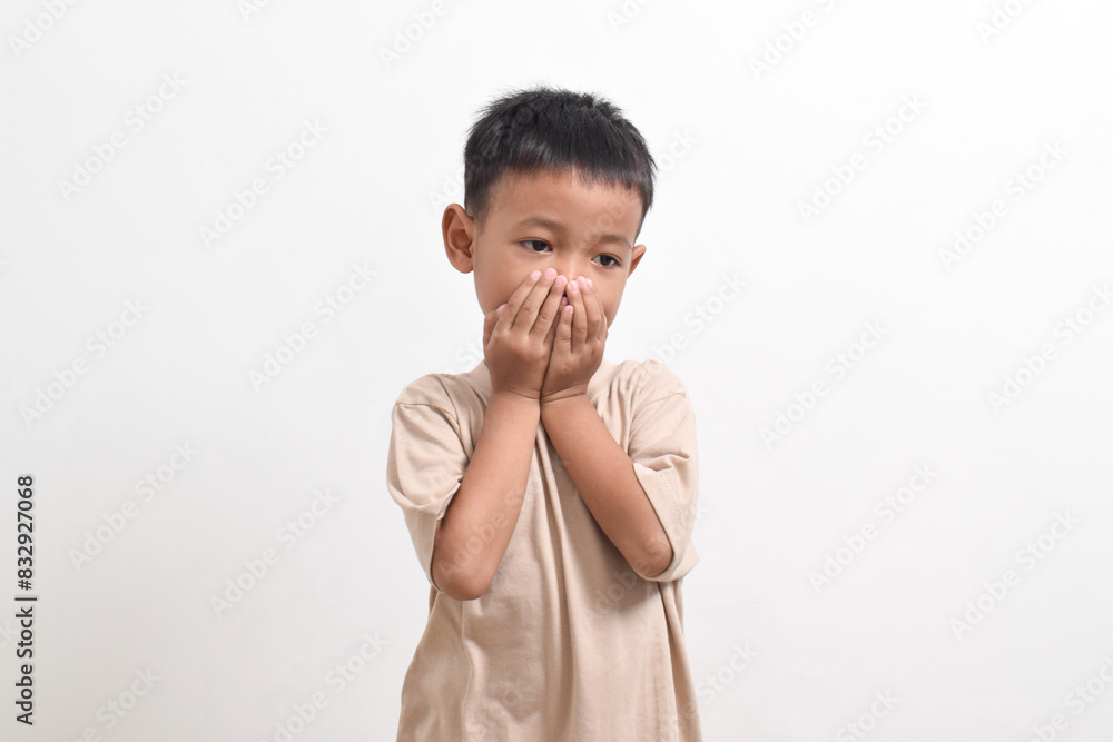Image of Asian child posing covering his mouth with both hands on a white background. portrait of an Asian boy Image of Asian child posing covering his mouth with both hands on a white background. portrait of an Asian boy