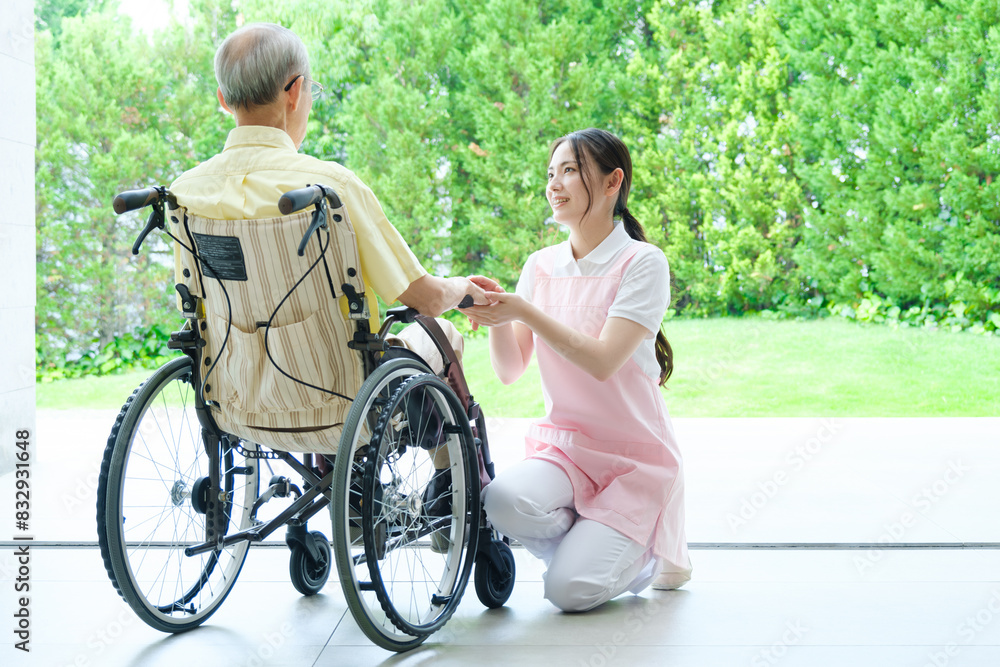 車椅子に乗った高齢者の介護をするヘルパー