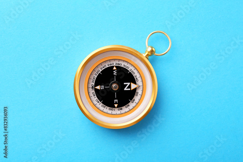 Compass on light blue background, top view. Navigation equipment