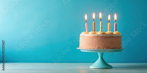 Birthday cake with four candles on a pastel blue background photo