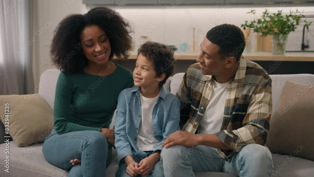 African American happy family portrait couple man father male dad mom woman mother female sitting indoor couch talking speak cuddle stroking head little boy child son kid parent tenderness living room African American happy family portrait couple man father male dad mom woman mother female sitting indoor couch talking speak cuddle stroking head little boy child son kid parent tenderness living room