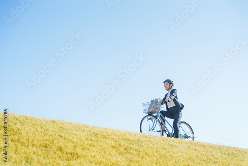 青空と自転車通勤するビジネスマン（ヘルメット）