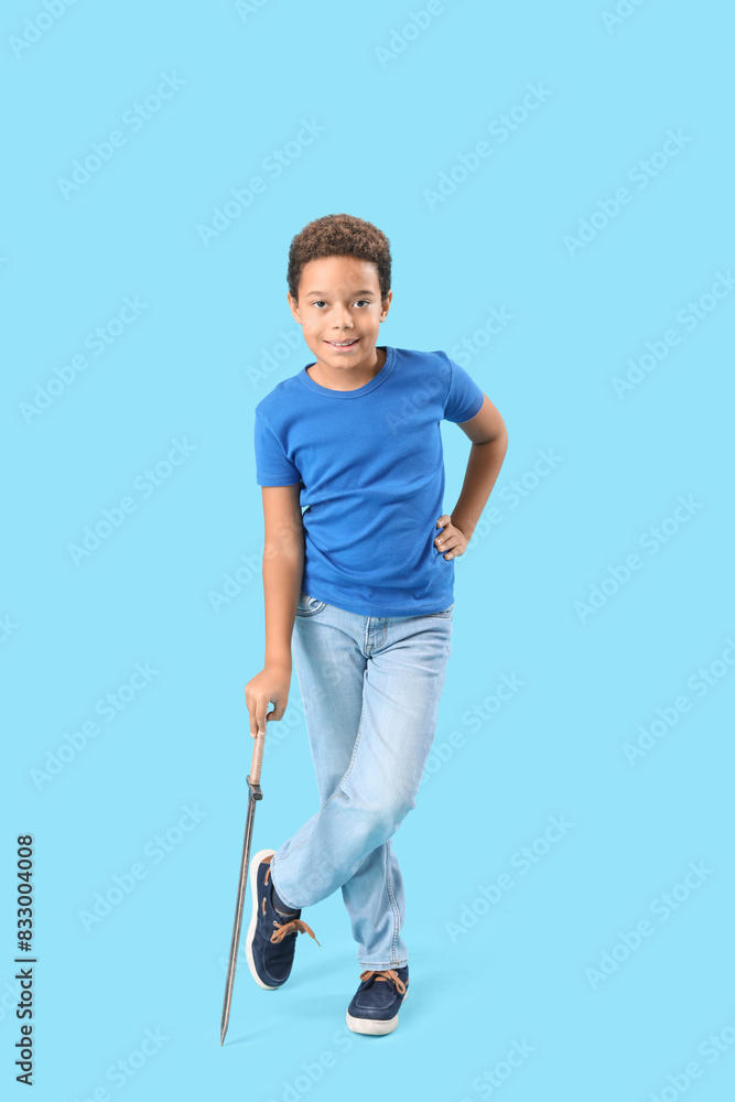 Little African-American boy with sword on blue background Little African-American boy with sword on blue background