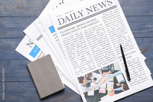 Newspapers with notebook and pen on blue wooden background photo