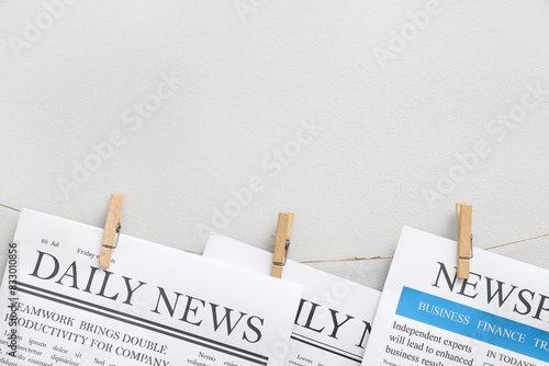 Newspapers hanging on rope against white background photo