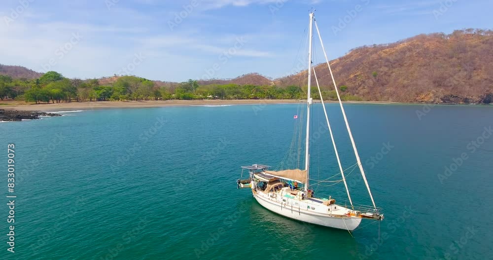 A monohull sailing yacht anchored in a calm water bay in Guacamaya, Costa Rica with no other sailing vessels anywhere around A monohull sailing yacht anchored in a calm water bay in Guacamaya, Costa Rica with no other sailing vessels anywhere around