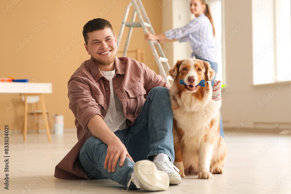Cute dog with roller and young couple during repair of their new house