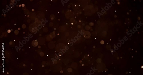 Golden bokeh particles drift and spin randomly as if moved by the wind, creating a mesmerizing visual effect. This 4K clip of computer-generated effects provides an ideal, dynamic background.