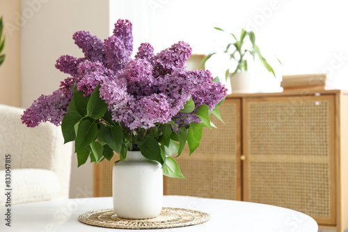 Fototapeta Vase with lilacs branches on coffee table in living room, closeup