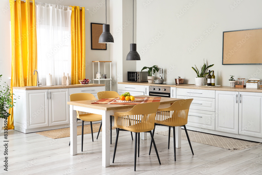 Interior of modern kitchen with white counters, dining table, yellow curtains, chairs and lamp Interior of modern kitchen with white counters, dining table, yellow curtains, chairs and lamp