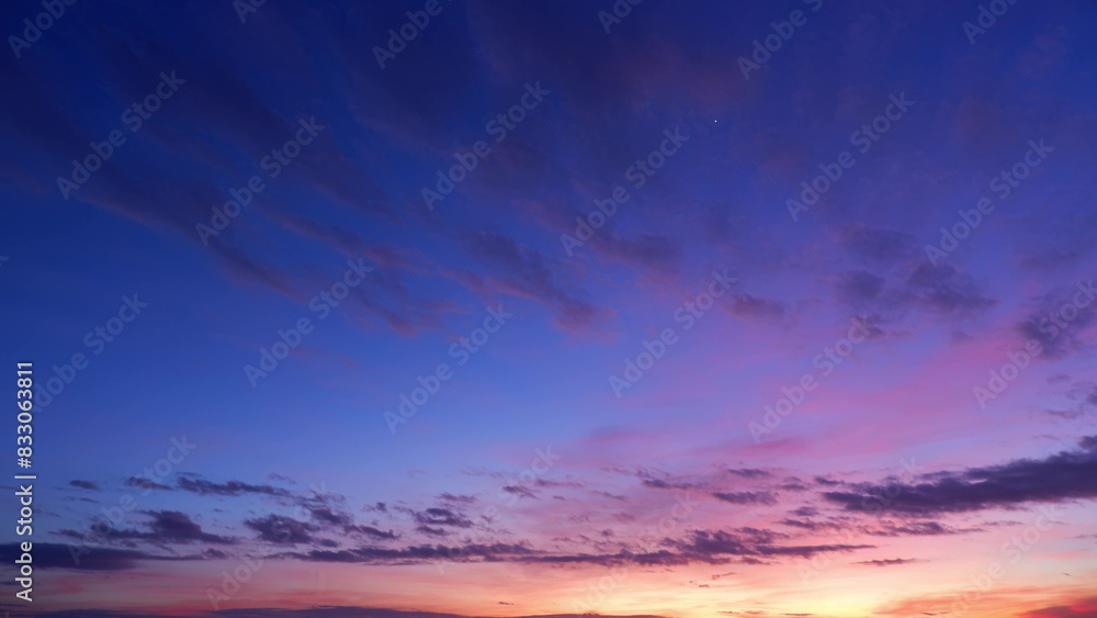 Fototapeta premium A stunning sunrise with a sky painted in deep shades of blue and purple, transitioning to lighter pinks and oranges near the horizon. Wispy clouds add texture and contrast. Sunrise sky background. 